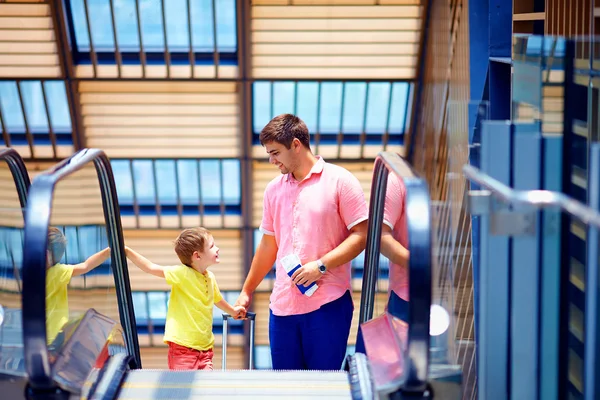 Familia feliz moviéndose en escaleras mecánicas, con tarjeta de embarque en las manos — Foto de Stock