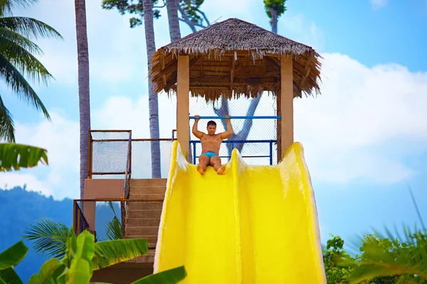 Hombre excitado divertirse en tobogán de agua en parque acuático tropical —  Fotos de Stock