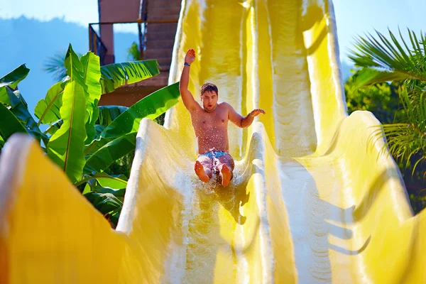 Hombre excitado divertirse en tobogán de agua en parque acuático tropical —  Fotos de Stock