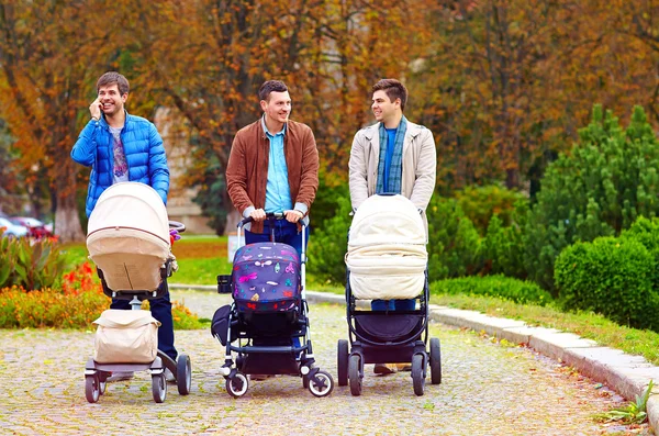 Tre glada fäder på city promenad i park — Stockfoto