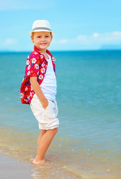 Cute fashionable boy stands in surf on summer beach — Stock Photo, Image