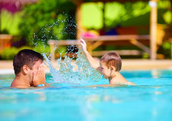 Pai e filho alegres se divertindo na piscina do parque aquático, férias de verão — Fotografia de Stock