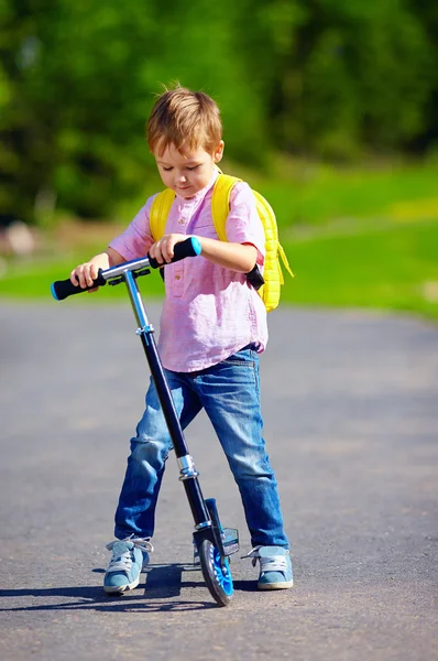 Ragazzo carino cavalcando uno scooter sulla strada, estate all'aperto — Foto Stock