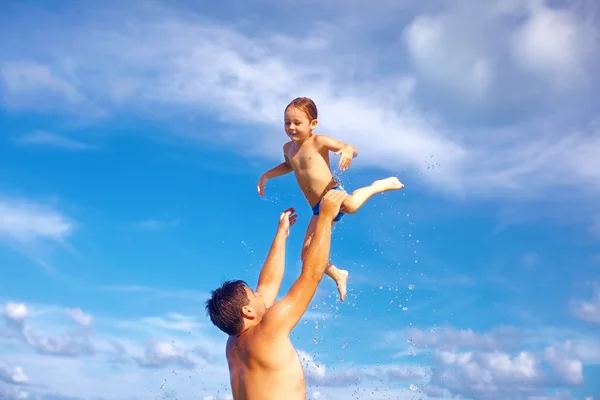 Веселые отец и сын веселятся в воде на тропическом пляже — стоковое фото