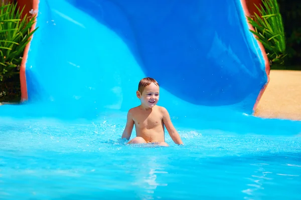 Glad liten pojke glidande i tropiska vattenpark — Stockfoto