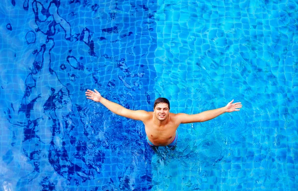 Glücklicher Mann genießt Urlaub, während er im Poolwasser steht, Blick von oben — Stockfoto