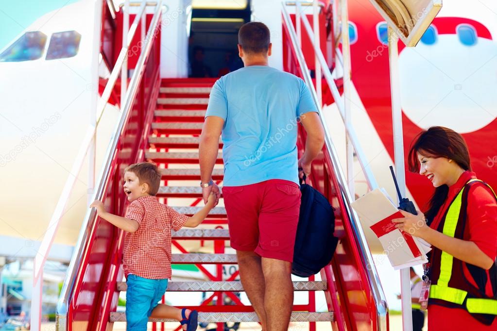 Family are boarding on airplane, female steward welcomes passengers