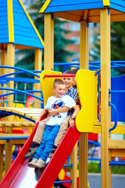 group of happy kids sliding in colorful playground