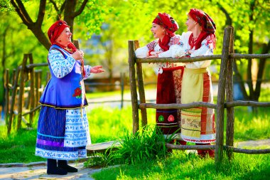 happy ukrainian women, dressed in traditional costumes, talking on the street
