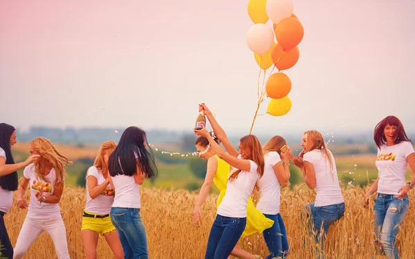 Group of happy women with bottle of champagne on summer field — Stockfoto