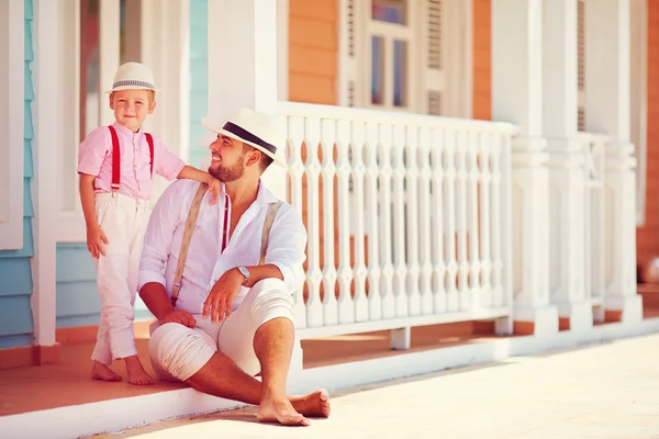 Modieuze vader en zoon zitten en praten over caribbean straat — Stockfoto