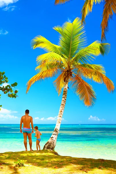 Father and son standing on tropical island beach — Stock Photo, Image