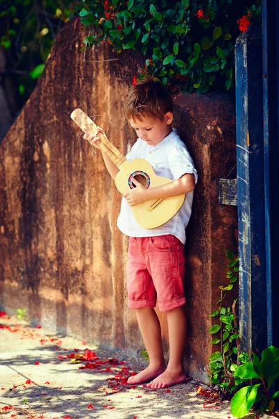 夏古いフェンスの近くギターを弾くかわいい少年 — ストック写真