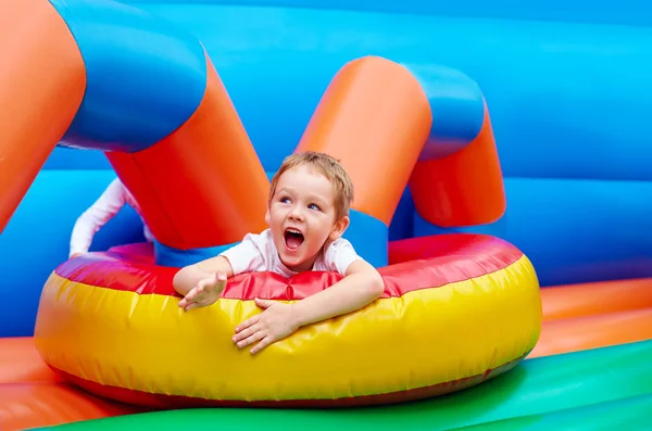 Menino animado feliz que se diverte no campo de jogos inflável da atração — Fotografia de Stock
