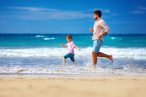 Щасливий збуджений батько і син бігають на літньому пляжі, насолоджуватися життям — стокове фото