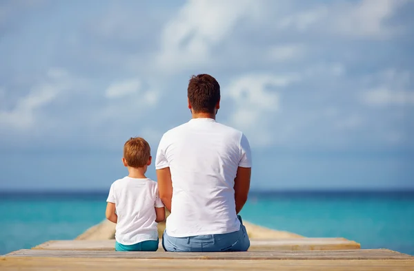 Pai e filho sentados no cais perto do mar — Fotografia de Stock