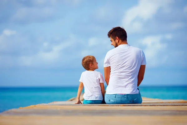 Vater und Sohn sitzen auf Seebrücke und reden — Stockfoto