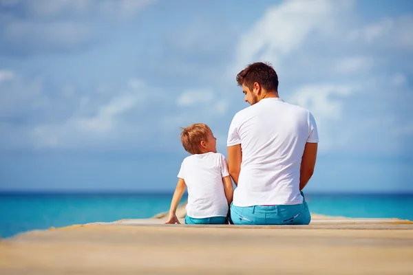 Szczęśliwy ojciec i syn siedzi na molo i dyskusja — Zdjęcie stockowe