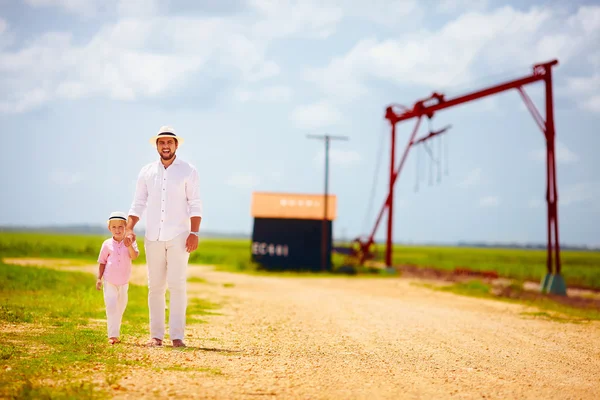 Father and son walking on country road among fields — Stock Photo, Image