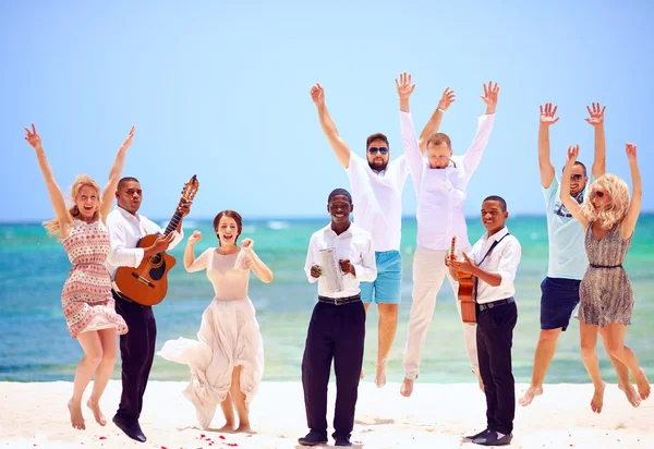 Groep van gelukkige mensen op viering de exotische bruiloft met muzikanten, op tropisch strand — Stockfoto