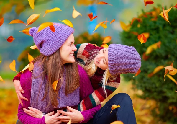 Amigos sonrientes divirtiéndose juntos en el parque de otoño entre hojas que caen — Foto de Stock