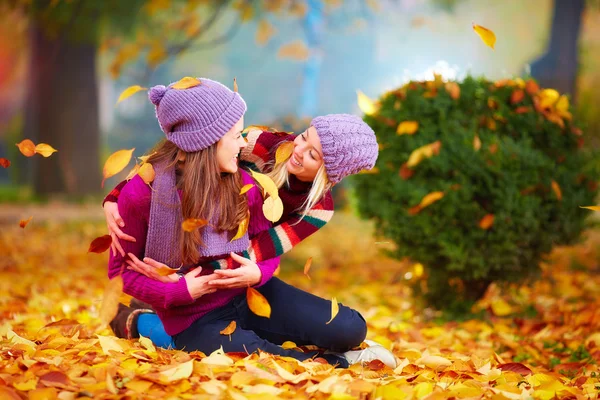 Amigos sonrientes divirtiéndose juntos en el parque de otoño entre hojas que caen — Foto de Stock