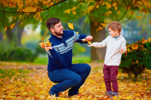 Gelukkig vader en zoon spelen in levendige herfst park — Stockfoto