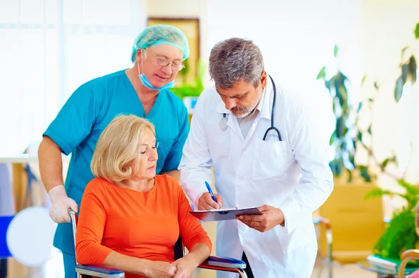 Mature female patient on wheelchair listens to doctor perscription medication — Stock Photo, Image