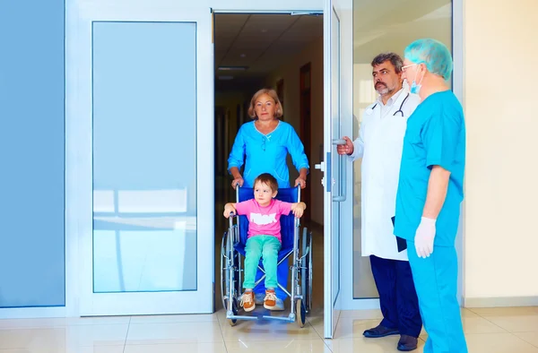 Enfermeiro cuidando de paciente pequeno em cadeira de rodas no hospital — Fotografia de Stock