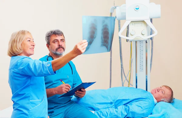 Médicos discutindo o radiograma de roentgen na sala de raios X com o paciente — Fotografia de Stock