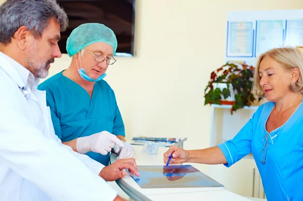 Medical staff consulting about health record at hospital desk — Stock Photo, Image