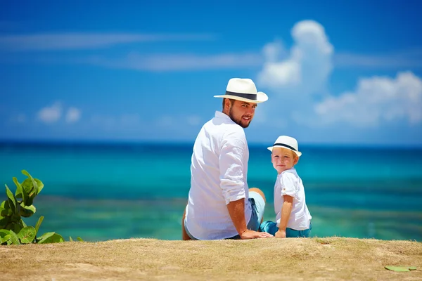 Feliz padre e hijo sentado cerca del mar durante las vacaciones de verano — Foto de Stock