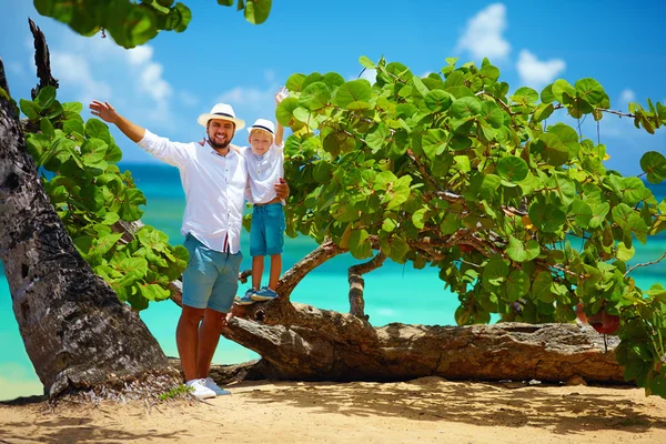 उष्णकटिबंधीय समुद्र तट के पास ग्रीष्मकालीन अवकाश पर मुस्कुराते हुए पिता और बेटा — स्टॉक फ़ोटो, इमेज