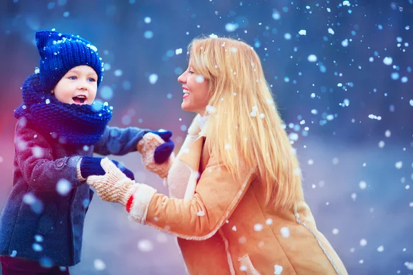 Feliz mãe e filho se divertindo sob neve de inverno — Fotografia de Stock