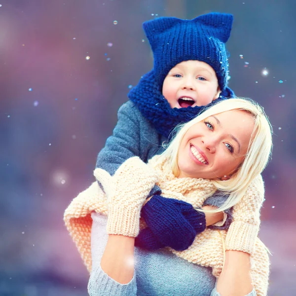 Felice donna e bambino che si abbracciano sotto la neve invernale — Foto Stock