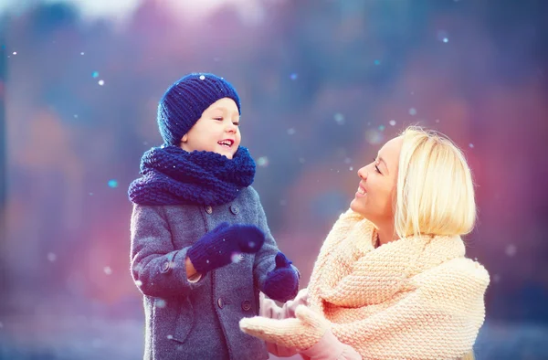 Счастливые мать и сын играют вместе под зимним снегом — стоковое фото