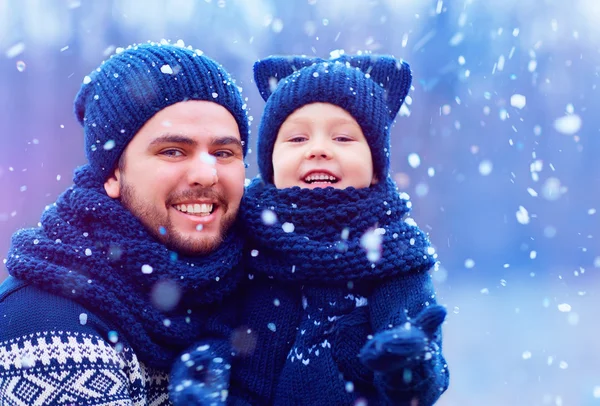 Feliz padre e hijo divirtiéndose bajo la nieve de invierno, temporada de vacaciones — Foto de Stock