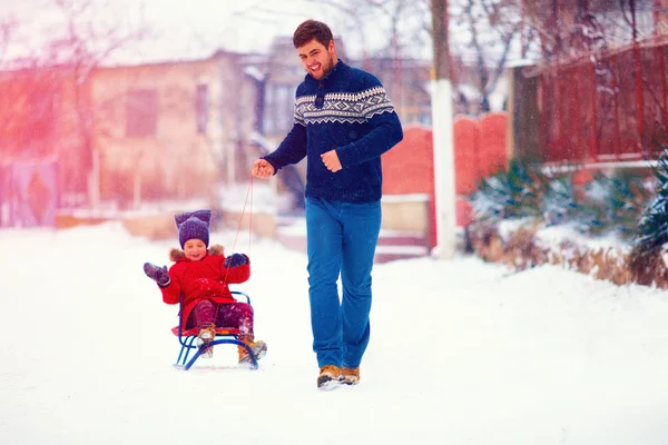 Щаслива родина катається на санях під зимовим снігом, на сільській вулиці — стокове фото