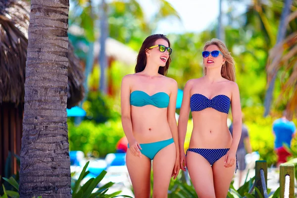 Happy young girls walking on tropical beach, during summer vacation — Stock Photo, Image