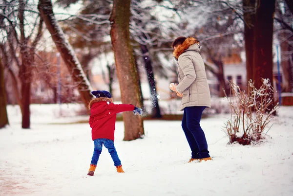 Активные отец и сын играют в снежки в зимнем парке — стоковое фото