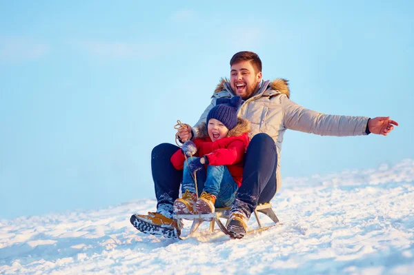 Familia feliz deslizándose cuesta abajo en la nieve de invierno — Foto de Stock