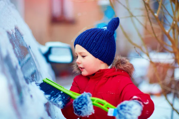 Jeune enfant brossage voiture couverte de neige — Photo