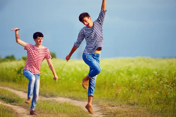 Happy male couple running through the summer field — Stock Photo, Image