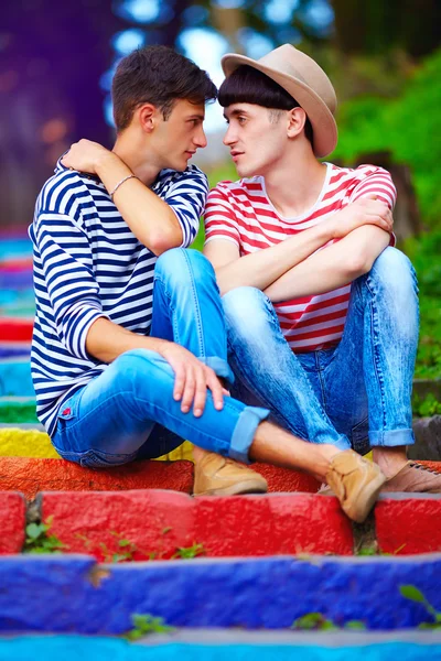 Junges männliches Paar sitzt auf Regenbogentreppe — Stockfoto