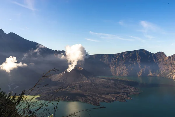 Active volcano, landscape with clouds in the morning, beautiful Mount Rinjani Gurung at Lombok Island, Indonesia. Small lake in the mountains, soft focus