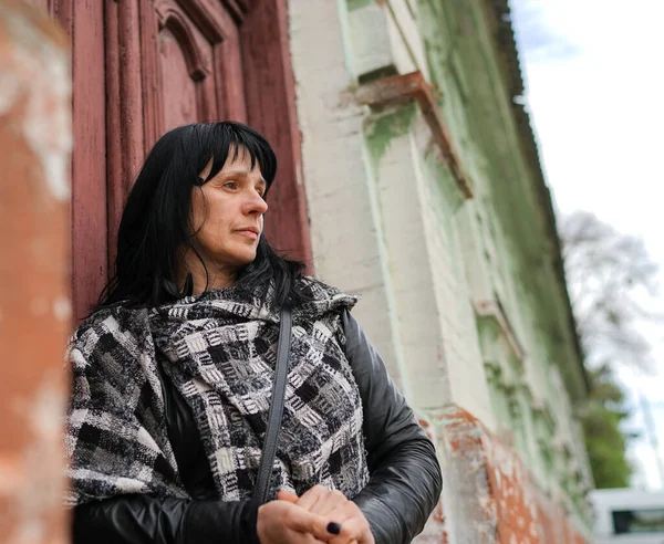 A beautiful adult woman at the front of the door, travelling in Europe, old rustic door in the abandoned house, a person knocking on the door to come in.