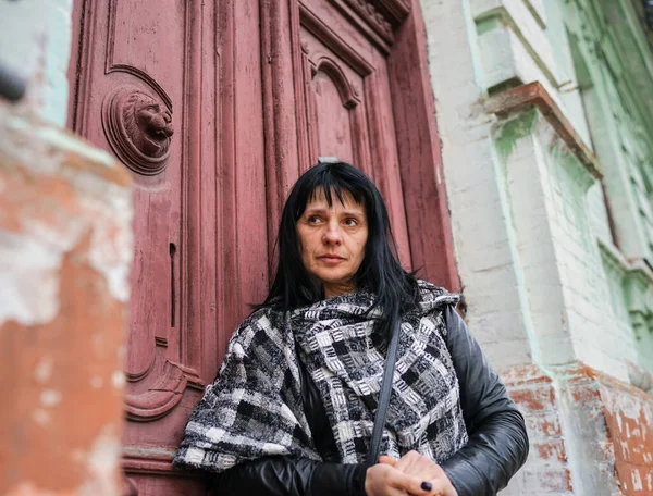 A beautiful adult woman at the front of the door, travelling in Europe, old rustic door in the abandoned house, a person knocking on the door to come in.