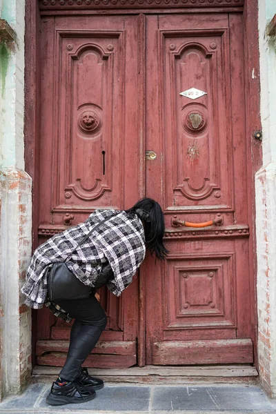 一个女人偷看门 一个人打开一个古老的门 古老的欧洲建筑 免版税图库照片