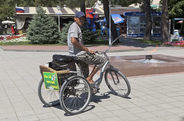 Balayeuse de rue sur un tricycle avec un panneau de nom "Nous sommes pour la ville propre !" sur le remblai Gelendzhik, région de Krasnodar, Russie — Photo