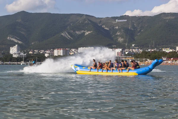 Horseback on an inflatable raft in Gelendzhik Bay. Driver of motorcycle aqueous drenches water attraction participants. Beach resort Gelendzhik, Krasnodar region, Russia